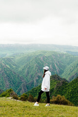 Fototapeta na wymiar Stylish woman tourist admires the mountain landscape