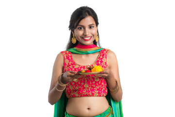 Beautiful Indian young girl holding pooja thali or performing worship on a white background