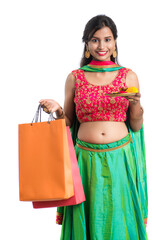 Beautiful Indian young girl holding and posing with shopping bags and pooja thali on a white...
