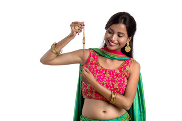 Beautiful girl showing Rakhi on occasion of Raksha bandhan on a white background. Sister tie Rakhi as symbol of intense love for her brother.