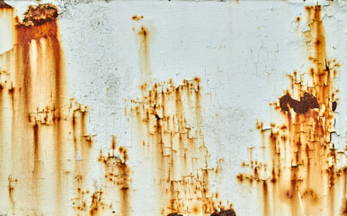 White paint on a metal surface cracks and peels to reveal rust underneath