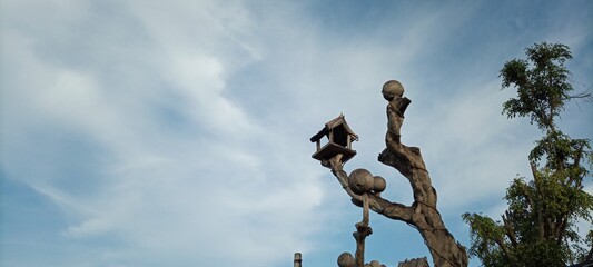 bird house on old wooden tree on cloudy blue sky