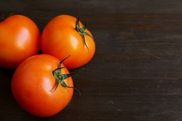 Closeup three of vibrant red tomato isolated on black wooden background with copy space