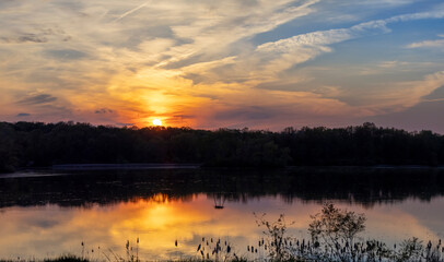 Naklejka premium Sunset with dramatic clouds in sky over lake