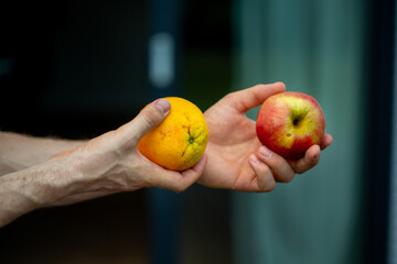 Comparing apples and oranges. Man hands holding apples and oranges.