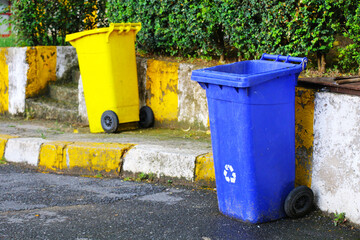 Fototapeta na wymiar Selective focus of yellow and navy blue trash cans in different recyclable colors used on the streets. colored trash cans