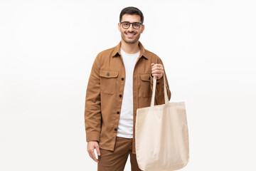 Young man holding cotton totebag or canvas grocery shopping bag with copy space for your logo