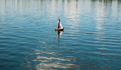Floating red navigational buoy on blue water of Dnipro River. Buoy in the river. Navigation equipment. Tranquil water surface.