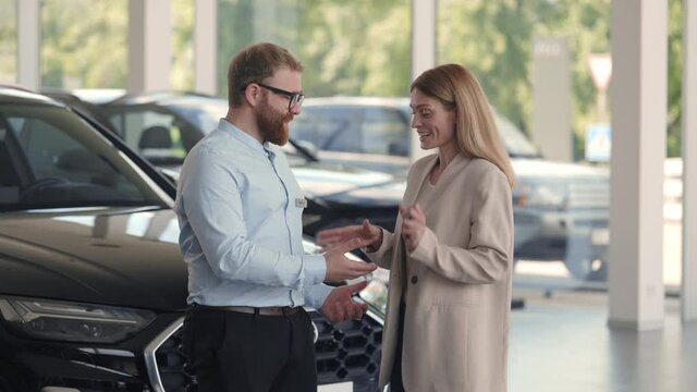 Manager giving keys from new car to female owner