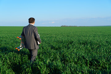 Fototapeta na wymiar businessman poses in a green field, he goes with the documents and ladder, freelance and business concept, green grass and blue sky as background