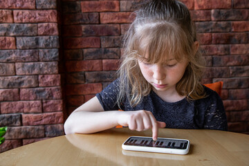 Little girl uses the piano app in the phone.