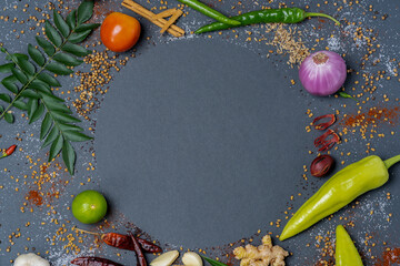 An aroma of basic necessities such as Chillies, Garlic, Ginger, Salt, Mustard, Curry leaves, Onions, Tomatoes, Capsicums, Fenugreek, Dried chillies and Cinnamon displayed in a circular pattern.