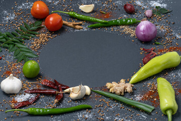 Circular pattern of Chillies, Garlic, Ginger, Salt, Mustard, Curry leaves, Onion, Tomatoes, Capsicum, Fenugreek, Dried chillies and Cinnamon.