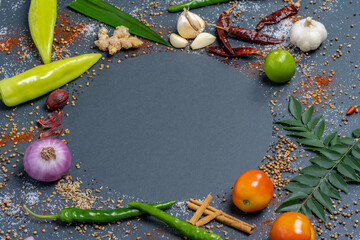 Circular pattern of Chillies, Garlic, Ginger, Salt, Mustard, Curry leaves, Onion, Tomatoes, Capsicum, Fenugreek, Dried chillies and Cinnamon.