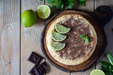 Sweet snack: Cheesecake with lime and chocolate on a wooden table. Top view.