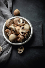 Raw champignon mushrooms on dark background