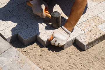 Paver is laying paving stones. Laying concrete paving stones.
