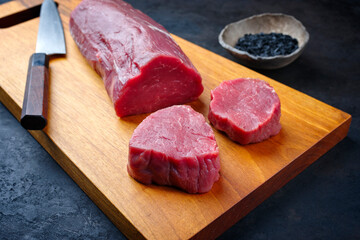 Traditional raw beef fillet steak natural with black salt as close-up on a modern design wooden...