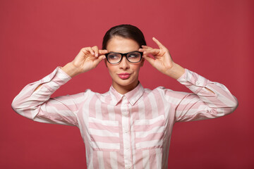 Fototapeta premium Young cheerful woman in glasses smiling on red background