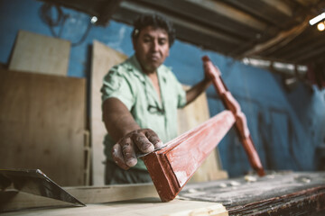 Mexican carpenter sanding a wood cross