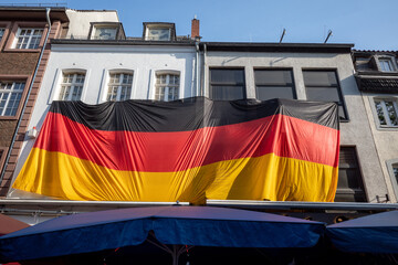 Big German Flag cover building over restaurant, pub or cafe in old town Düsseldorf during celebrate German National football match. 