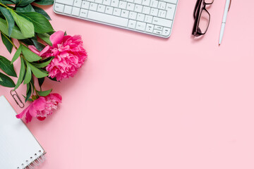 Obraz na płótnie Canvas Laptop, accessories and bouquet of beautiful peonies with glasses and headphones on pink background. Flat lay of working place.