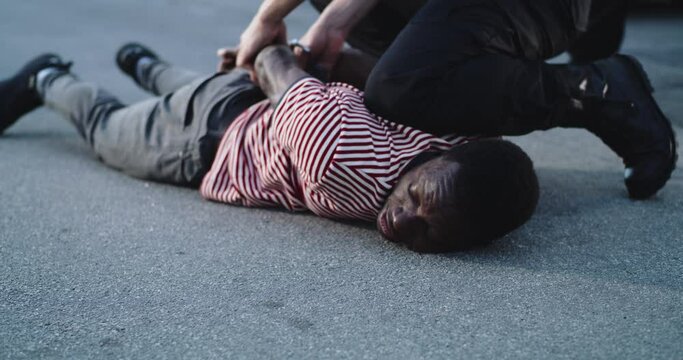 Crop police office restraining African American convict