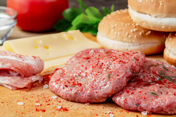 Process of cooking homemade burgers, meatballs, tomatoes, cheese and other ingredients on a wooden background, close up