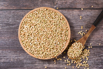 Raw uncooked buckwheat in a bowl on wooden background