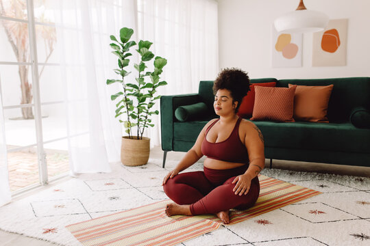 Plus size woman practicing meditation at home