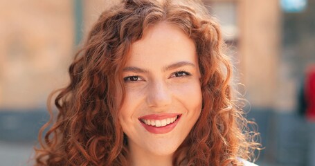 Portrait of beautiful young girl of caucasian ethnicity with curly ginger hair standing on the warm...