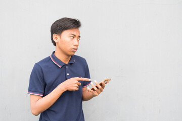 Indonesian guy pointing his index finger to the pho with a suspicious facial expression