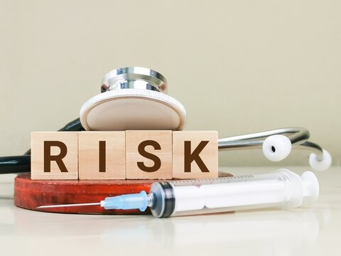 Text risk on wooden cubes with syringe and stethoscope. Medical risk management concept.