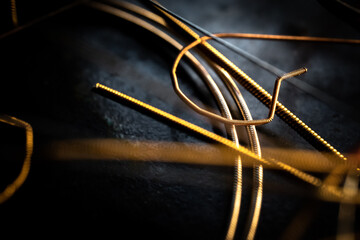 Macro Closeup of Cut End of Bronze Acoustic Guitar String Laying on Used Strings