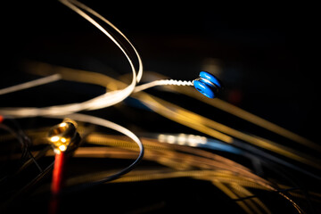 Macro Closeup of Blue Ball End of Bronze Acoustic Guitar String in Front of Group of Loose Used Strings