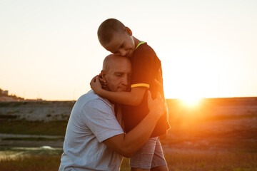 Son and dad standing against the backdrop of a colorful sunset. The relationship between father and son. Family's soulful walk in nature in the rays of the setting sun