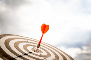 Close up shot red darts arrows in the target  of dartboard center on dark blue sky background....