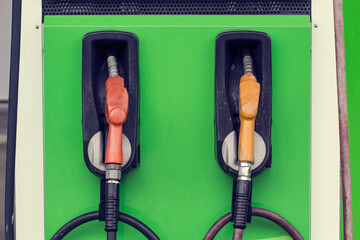 yellow and red petrol gas pump nozzles in a service station background green