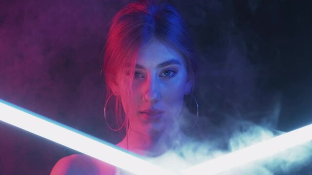 Color light face. Cyberpunk beauty. Synthwave party. Pink blue neon glow woman in smoke motion white LED lamp illumination on dark background.