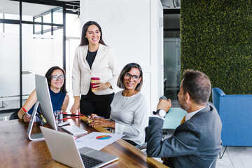 Group of Hispanic business people with transgender woman in wheelchair smiling in business meeting in the office, in disability concept and disabled people