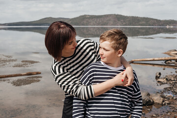 Mom hugs her son on the riverbank.