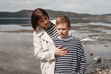 Fototapeta na wymiar Mom hugs her son on the riverbank.