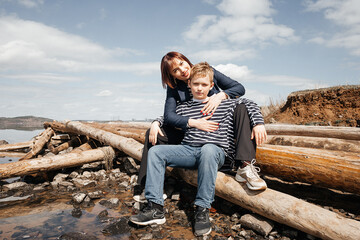 Mom hugs her son on the riverbank.