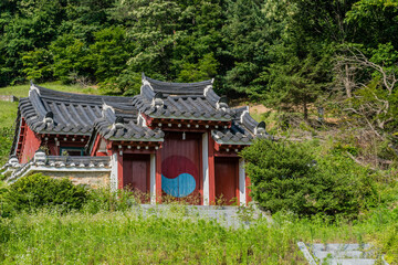 Oriental gate building with tiled roof on small hill in rural countryside