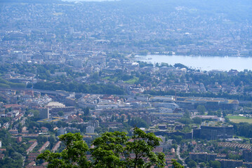 Obraz premium Panoramic view over City of Zurich seen with lake Zurich seen from local mountain Uetliberg on a hazy summer day. Photo taken June 18th, 2021, Zurich, Switzerland.