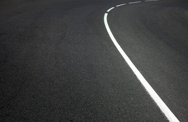 Obraz premium Turning asphalt road with marking lines and tire tracks.
