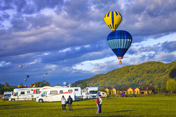 Obraz premium Colorful hot air balloons flying over the campsite at sunrise