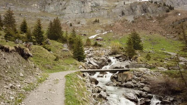 Hiking trail crossing river via little bridge in the Swiss Alps