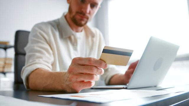 Blurred company accountant types on laptop holding bank card