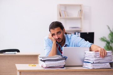 Young male employee unhappy with excessive work in the office